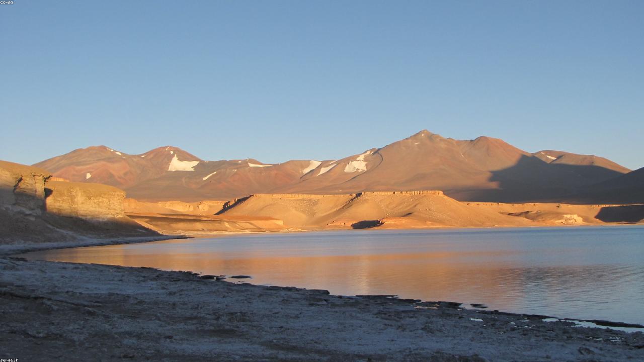 Deserto do Atacama ao amanhecer, com vulcões ao horizonte