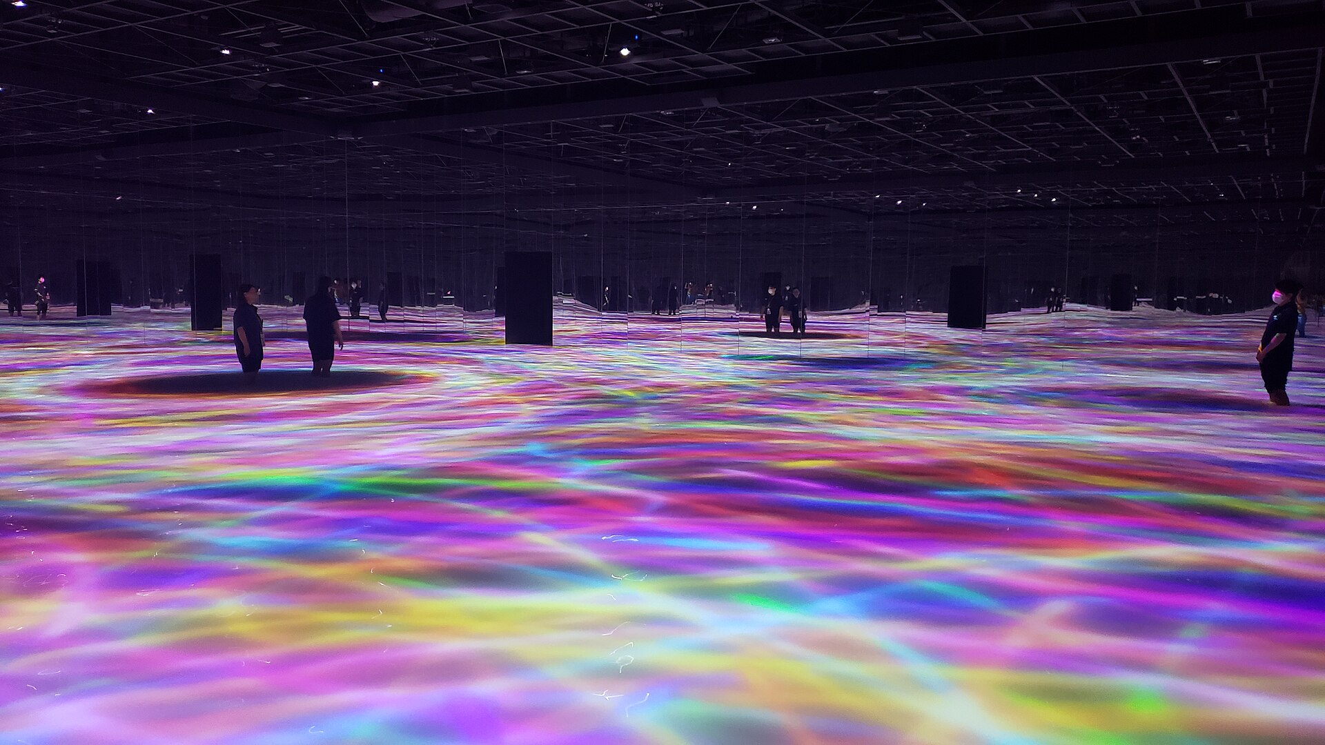 Visitantes caminhando sobre a água colorida por projeções no TeamLab Planets, em Tóquio